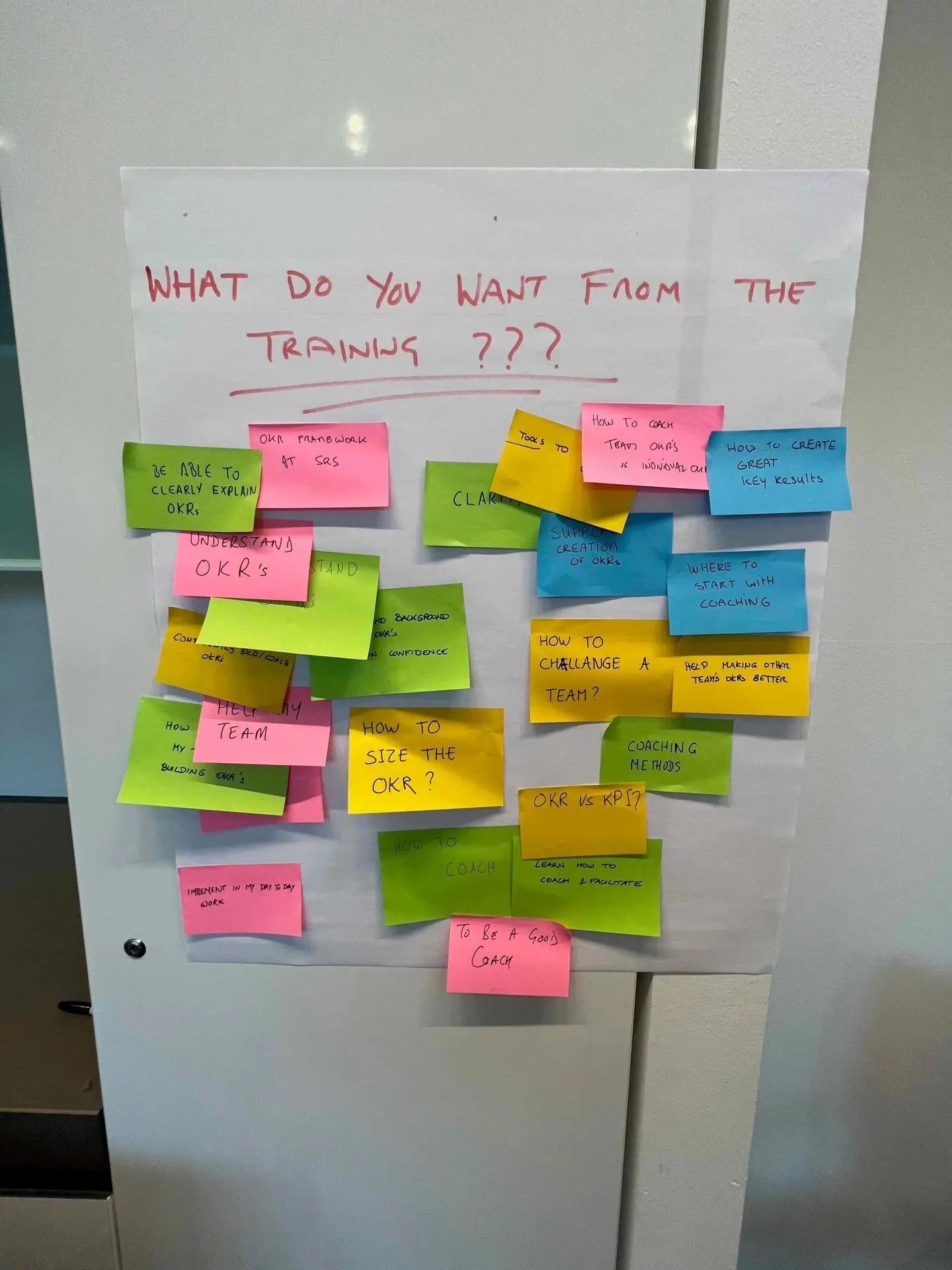 Trainer guiding a team through OKR planning using sticky notes and a flipchart during a workshop