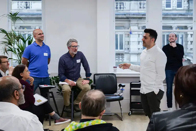 An OKR Consultant delivering OKR training to a group of professionals in a modern office setting